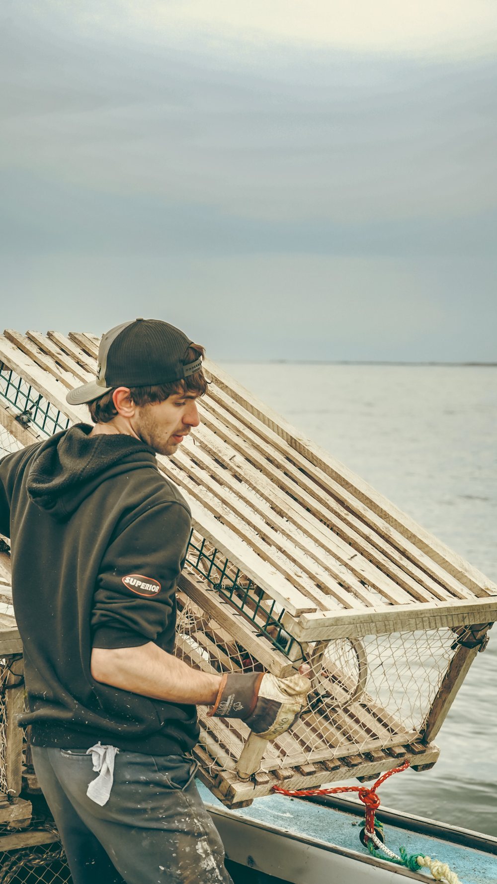 A Seaside Fresh fisherman hauling a wooden lobster trap aboard the boat